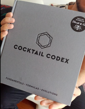 A reviewer holding a gray book with black text on the cover that says