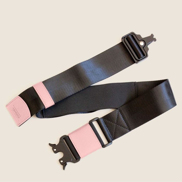 A pink travel belt with a secure latch, offering a convenient solution for carrying additional bags.