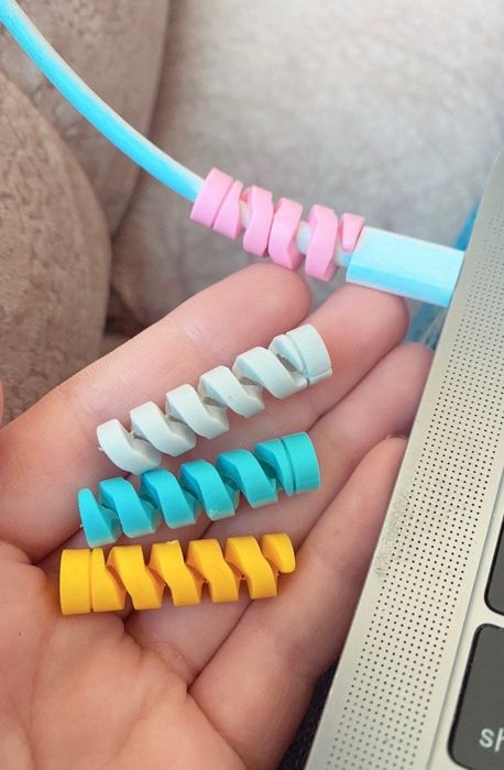 Four spiral-shaped charger protectors, one of which is wrapped around a Mac charger at the charging point.