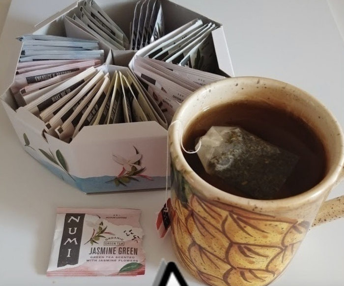 A cup of tea placed beside the tea box