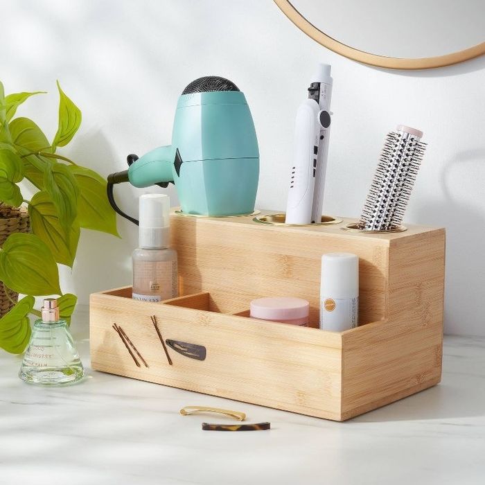 A wooden organizer for hot hair tools, neatly holding various styling tools and hair products.