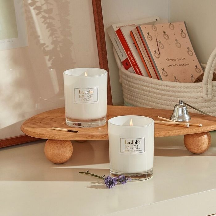 Lavender, eucalyptus, and jasmine-scented candles placed on a wooden tray