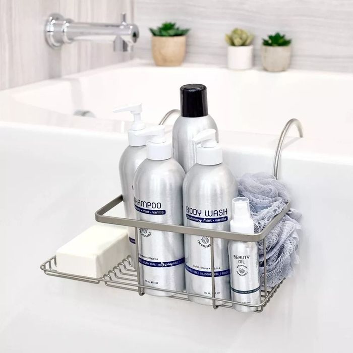 A silver over-the-bath caddy holding various bath products and a bar of soap.