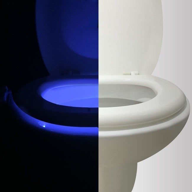A toilet half-lit by daylight, the other half glowing from the motion-activated light in the dark
