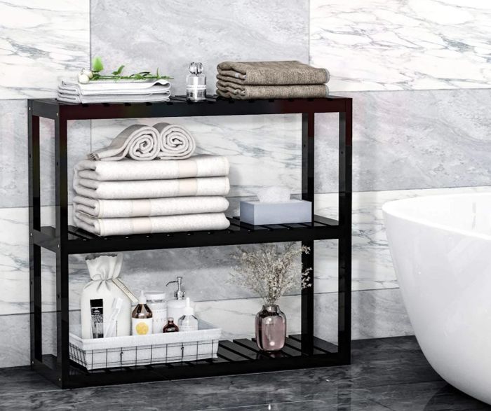 A black bathroom shelf with towels and other bathroom essentials