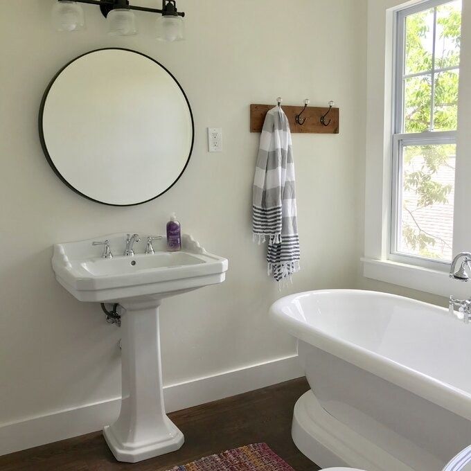 A reviewer's black circular mirror mounted above a bathroom faucet