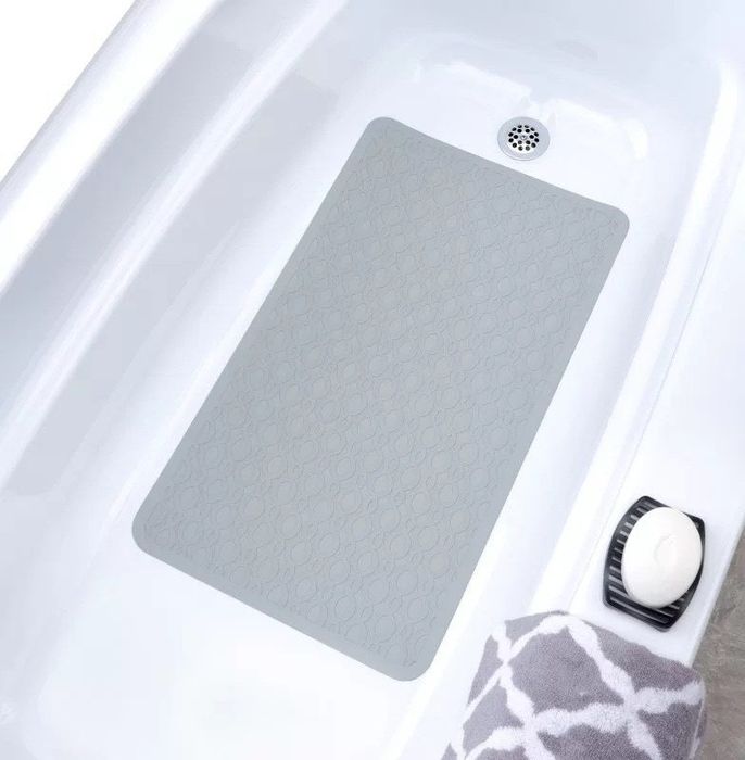 a light-colored shower mat placed on a white bathtub
