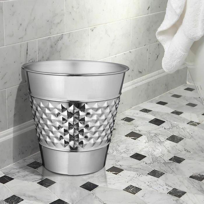 a nickel chrome wastebasket sitting on a black and white checkered tiled floor
