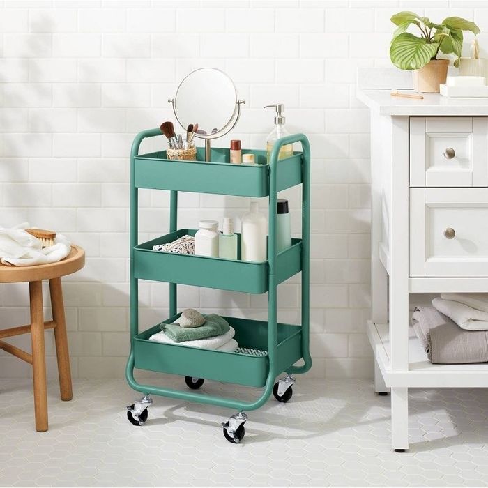 A green utility cart filled with toiletries, sitting in a bathroom.