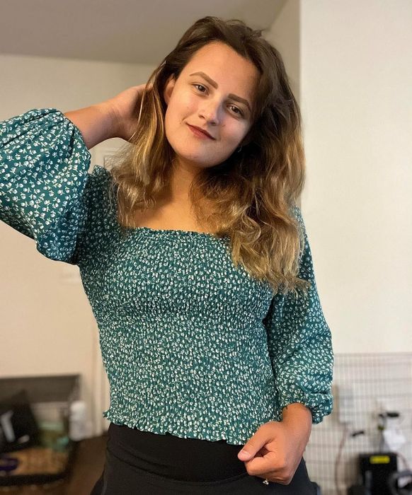 A reviewer showcasing the green version of the top, paired with a black flared skirt