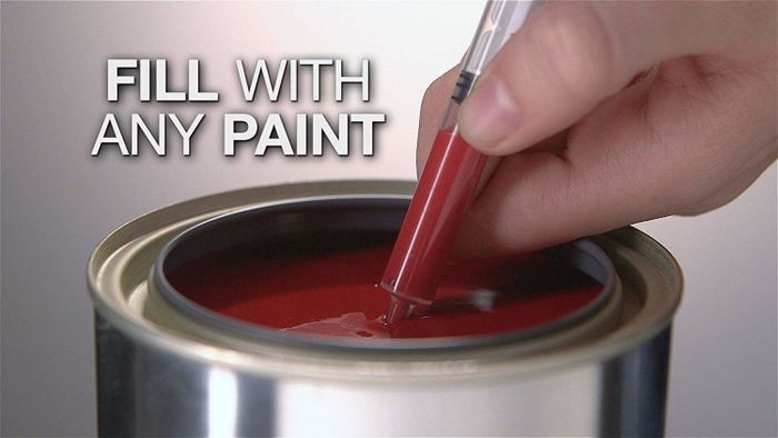 a person filling the paint pen with red paint