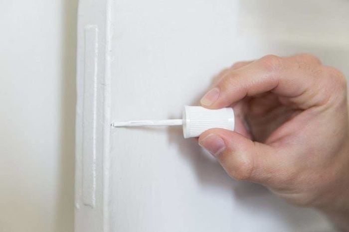 A person is applying white touch-up paint.