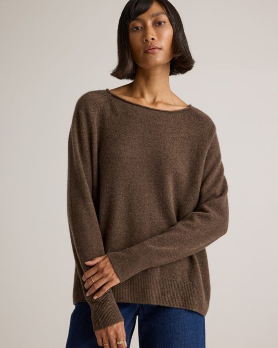A person rocking a relaxed-fit sweater and jeans, striking a neutral pose