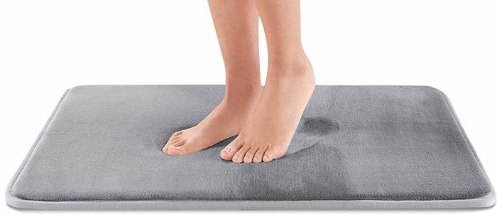 A person stepping onto a gray mat.