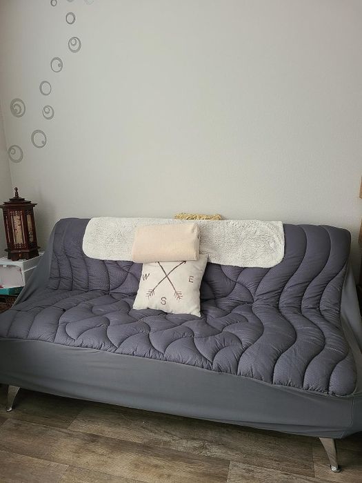 The reviewer's image of the mattress topper placed on the couch