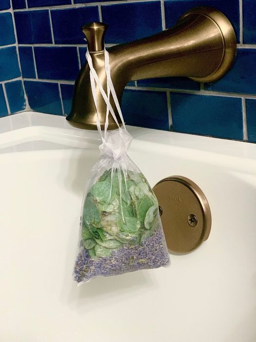 A pouch containing eucalyptus and lavender hanging from a shower nozzle.