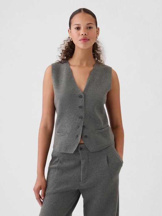 A model in a sleeveless textured vest and matching trousers, hands tucked in pockets, exuding confidence while posing.