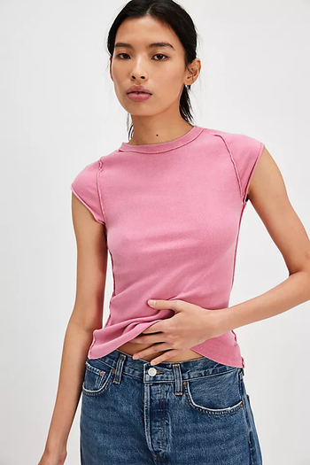 A person strikes a pose in a sleeveless top and jeans, hand on their waist, featured in a shopping article.