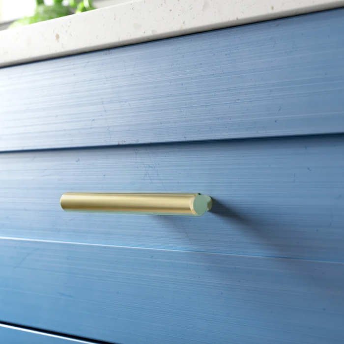 A gold handle on a blue dresser drawer.