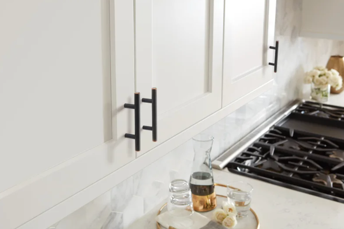Black pull bars on a white kitchen cabinet.