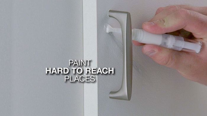 A person is using a paint pen to apply white paint to a door.