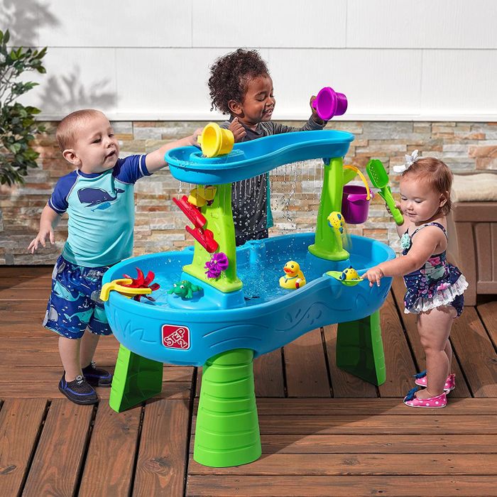 Three children having fun playing with a water table that features a maze and waterfall