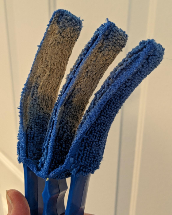 Reviewer holding the blue duster brush, now covered in dust from cleaning