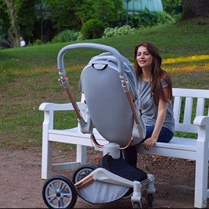 A person sitting on a bench with the stroller bed reclined to an upright position.