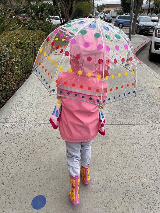 A reviewer image of a child walking with the umbrella held over their head for shelter