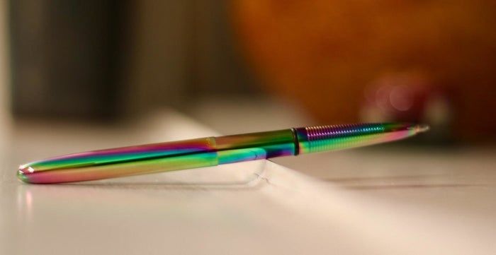 The metallic, rainbow-colored pen resting on a table