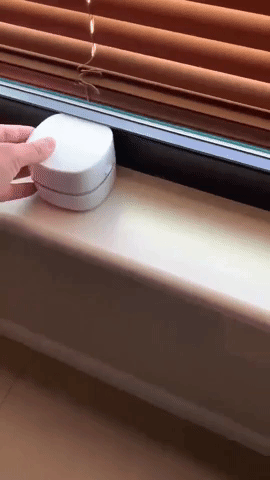 A reviewer using the desktop vacuum to clean a window sill