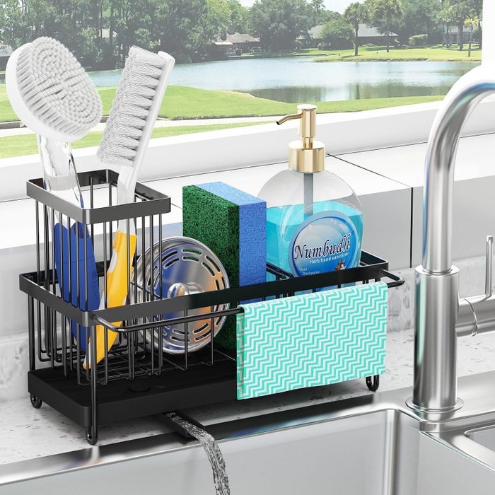 A kitchen sink area with a sleek black metal organizer that holds dish brushes, sponges, a soap dispenser, and a patterned dishcloth, keeping everything neat and accessible.