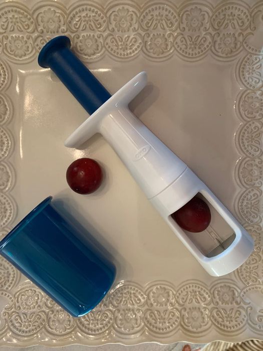 Image of a grape cutter alongside a grape