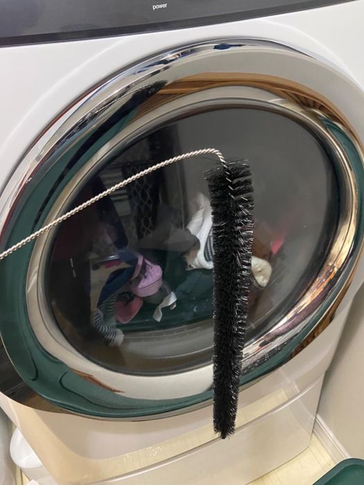 Reviewer photo showing the black lint brush placed in front of a full dryer