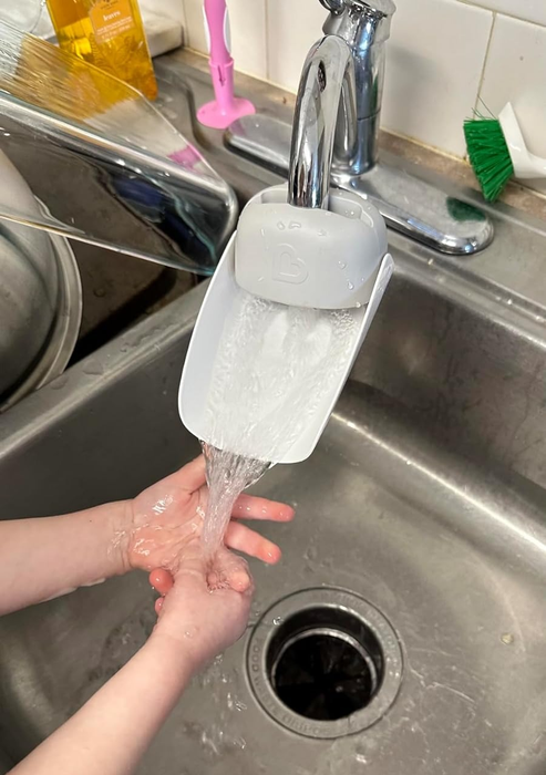 A child's hands washing under a faucet with an extender attached