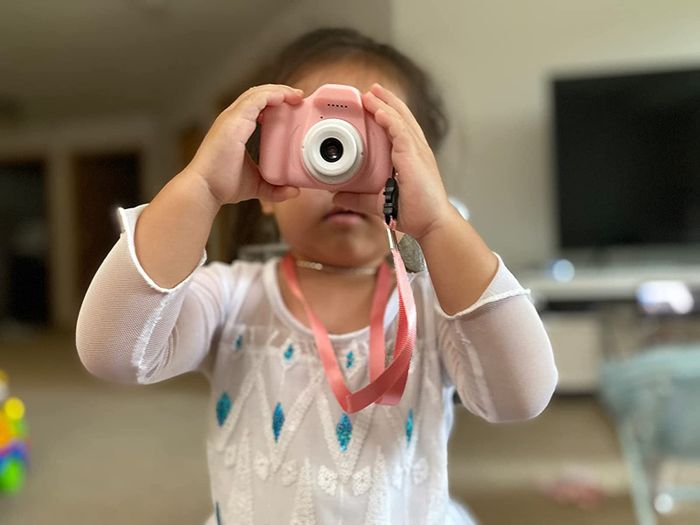 A reviewer’s image showing a child holding a pink camera up to their face.