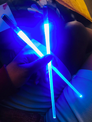 Blue lightsaber chopsticks emitting a soft glow in a dimly lit room.