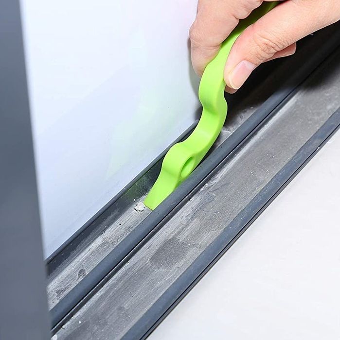 A model using the scraper side of the tool to clean a window ledge, removing debris effortlessly