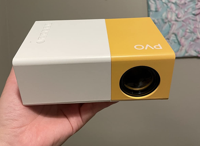 A customer review image showing them holding the mini projector in their hands.
