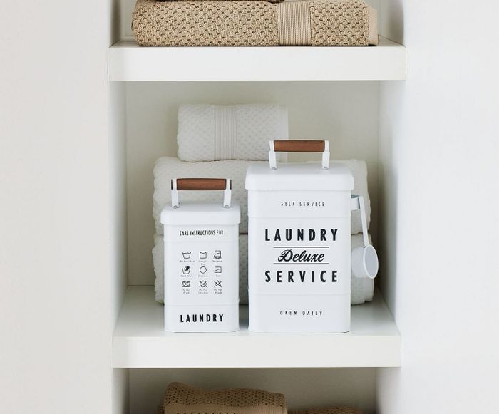 A shelving unit holding neatly folded towels and laundry containers, all clearly labeled with 
