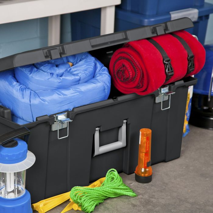 An open toolbox filled with a blue sleeping bag, a red sleeping bag, a lantern, rope, and a flashlight. Perfect for organizing camping gear.