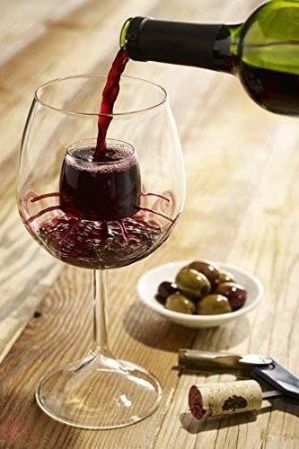 A wine glass with an aerating piece in the center, wine flowing through the center and spreading outward across the glass.