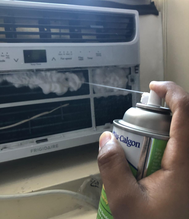 A reviewer spraying an air conditioner with the foaming coil cleaner