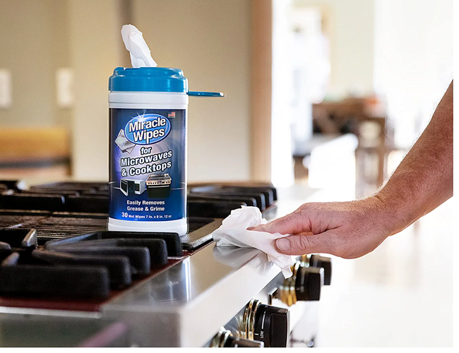 A model cleaning the front of a stove using appliance wipes for a spotless finish.