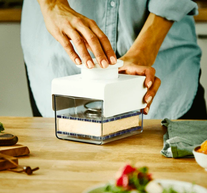 Tofu being pressed inside a plastic container.