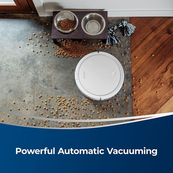Round robot vacuum cleaning up scattered pet food