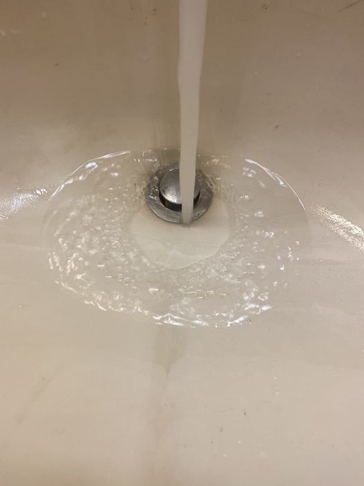 On the left, a drain clog dissolver poured into a white sink