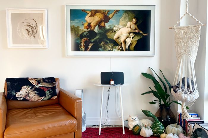 The television with a white frame, featuring a classic painting in the center