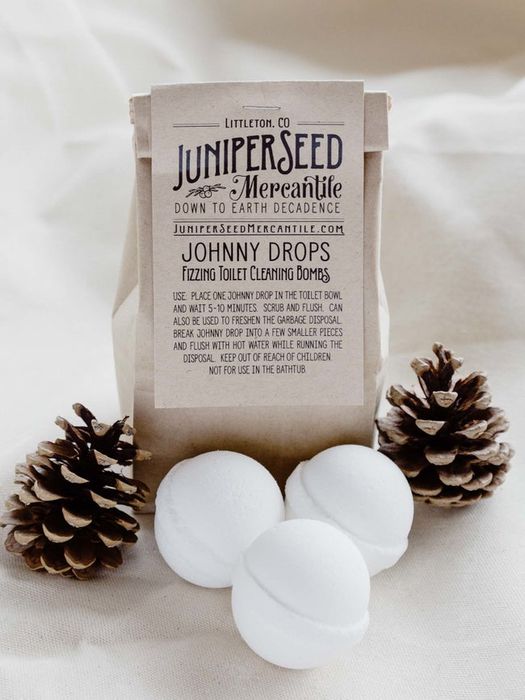 Three white spherical toilet bombs placed in front of their packaging