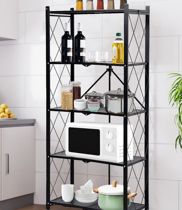 A metal kitchen storage rack with multiple shelves holding a variety of items, including spices, wine bottles, glasses, a microwave, bowls, and jars.